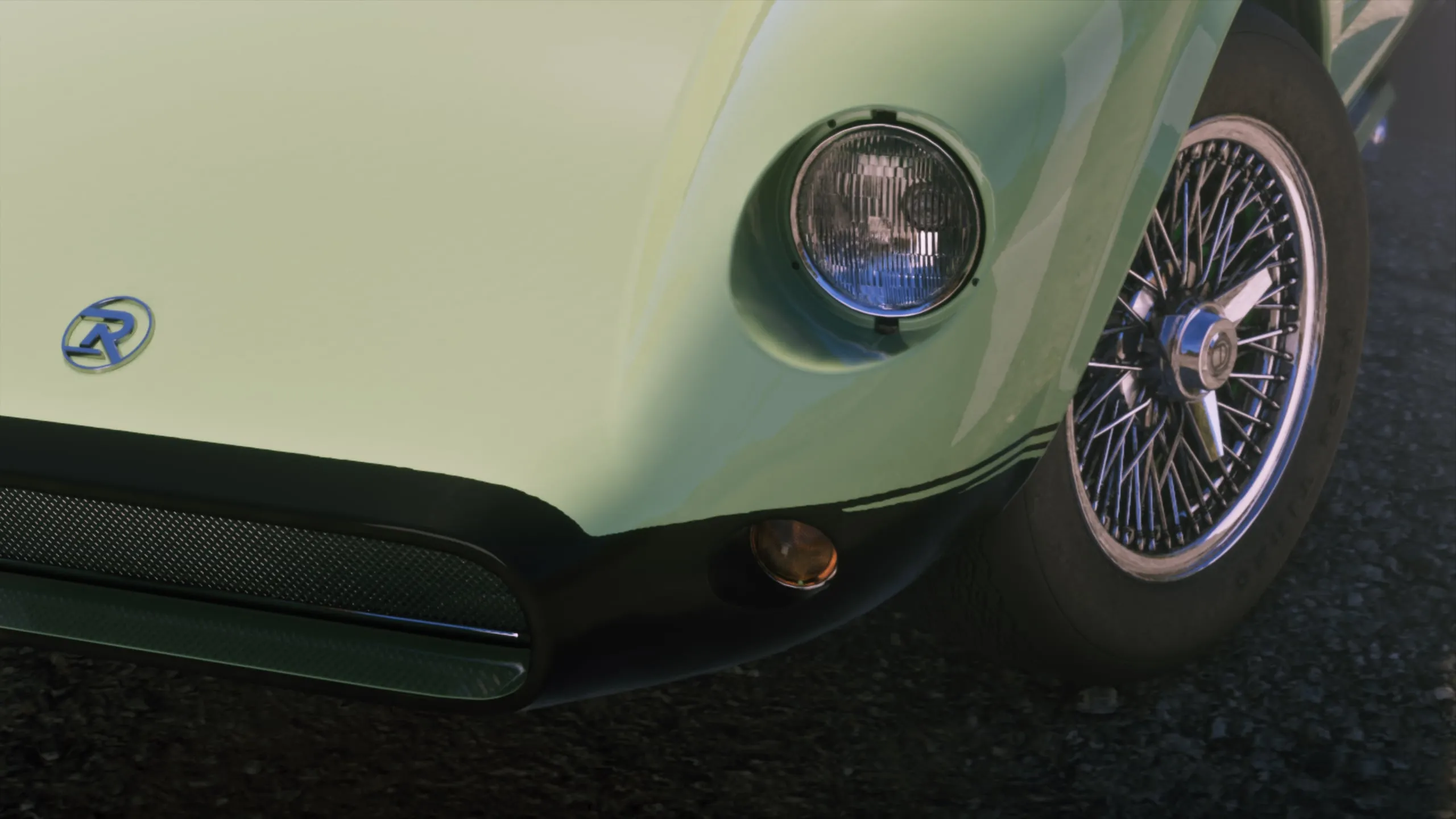 A pale green classic roadster with an R badge and wire wheels